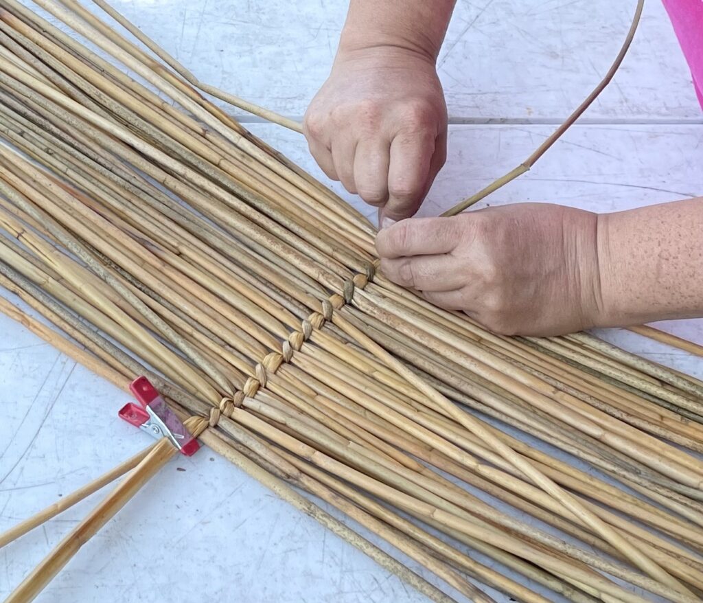 Hands tying branches together — a metaphor for LEAF's work connecting artists and community